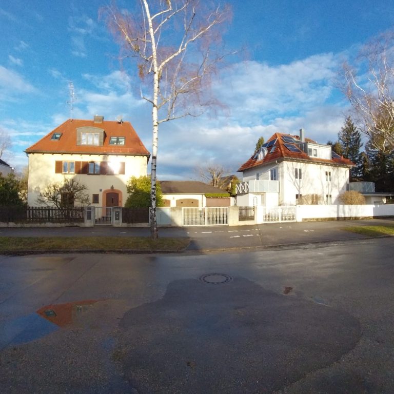 Zwei elegante Wohnhäuser mit roten Dächern und einer klaren blauen Himmel hinter ihnen.