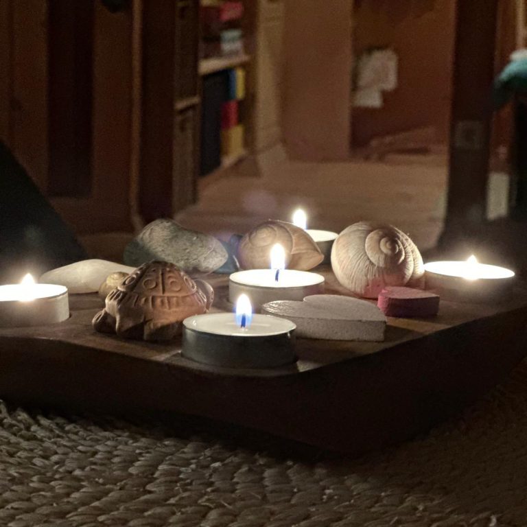 Eine kleine Anordnung aus Kerzen, Muscheln und dekorativen Objekten auf einem Tisch.