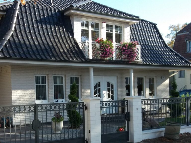 Feng Shui für Menschen in ihren Häusern Charmantes Haus mit Erker, Balkon und blühenden Blumenkästen. Eingezäunter Garten.