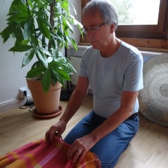 Eine Person sitzt auf dem Boden und hält die Füße eines Patienten neben einer Pflanze.