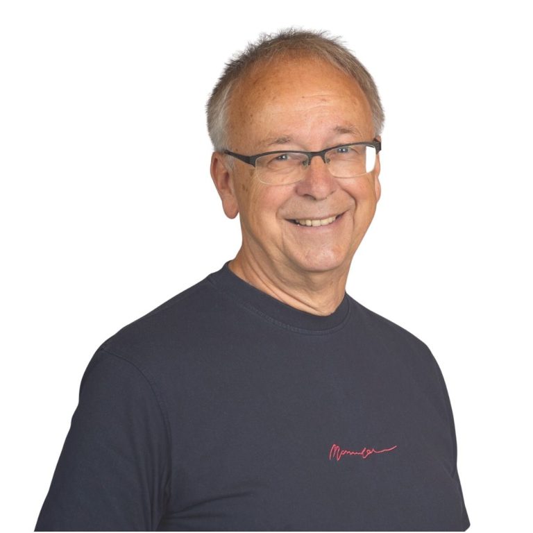 Andreas Bieler Lächelnder älterer Mann mit Brille, schwarzem T-Shirt und grauen Haaren.