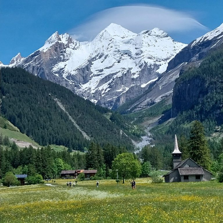 natürliches Feng Shui Berglandschaft mit schneebedecktem Gipfel, grünen Wiesen und einer kleinen Kirche. Das ist ein kraftvolles Feng Shui